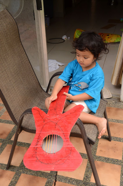 showing off her red cardboard guitar