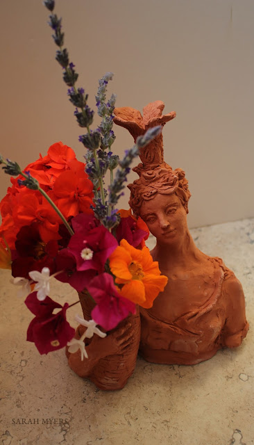 Lady with Plumes, Sarah Myers. From slightly above. lady, plumes, basket, sarah, myers, art, arte, artist, terracotta, sculpture, vase, escultura, skulptur, flowers, bouquet, arrangement, beautiful, feathers, woman, figurative, decor, decorative, contemporary, modern, red, earthenware, clay, face, eyes, cornucopia, lavender, nasturtiums, jasmine, bougainvillea, spring, printemps, primavera, handmade, bright