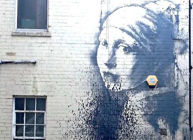Slightly defaced Banksy wall art 'Girl with a Pierced Ear Drum'