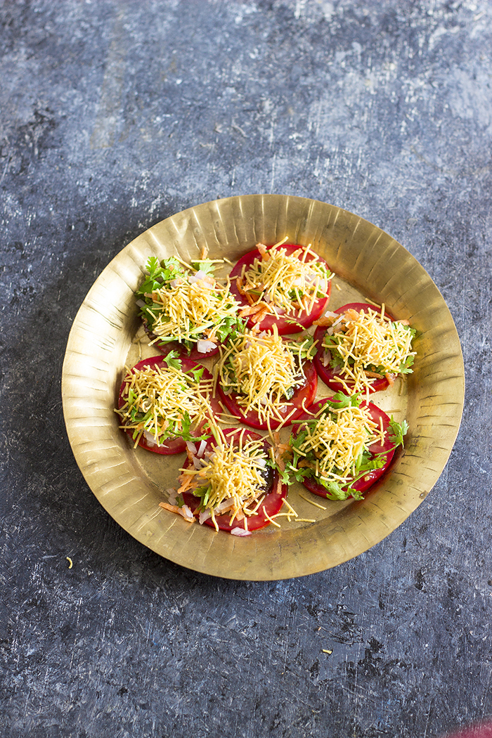 Bangalore Street food made by topping tomato slices with a mix of sweet and spicy chutneys and topped off with salted puffed rice