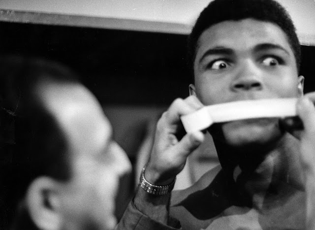 Muhammad Ali (then known as Cassius Clay) getting his mouth taped by trainer Angelo Dundee during the weigh-in before his fight with Doug Jones (March 1963) Photograph by George Silk