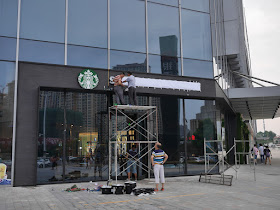 workers putting up lettes for a Starbucks storefront sign in Bengbu