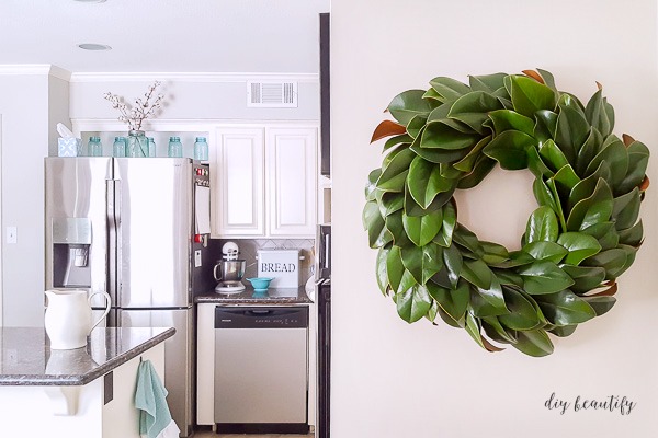 DIY magnolia wreath hanging on kitchen cabinet
