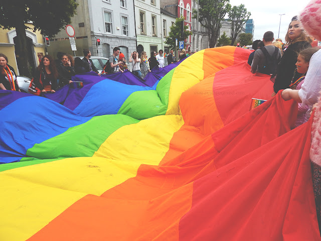 giant rainbow lgbti flag held by many people