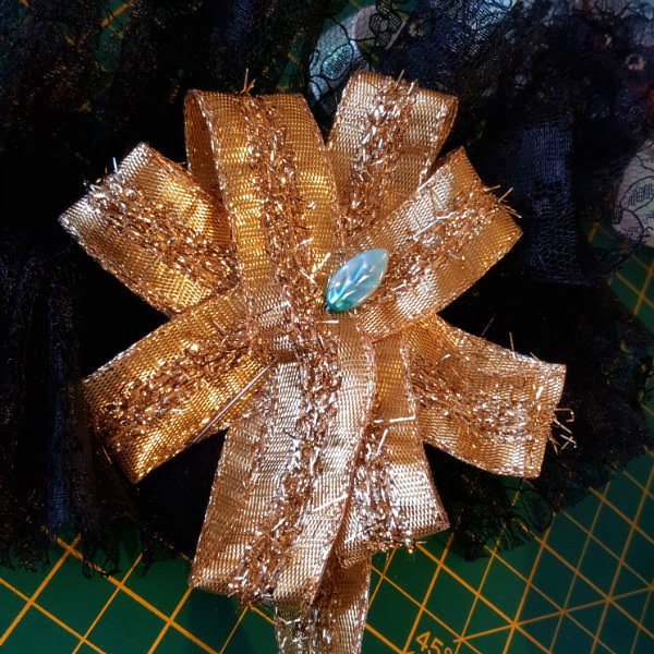 Deciding on a trim; gold ribbon rosette gold wired ribbon pinned into a rosette shape on the black lace cuff