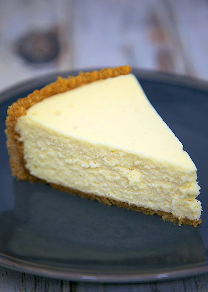 A slice of delicious homemade cheesecake on a black plate.
