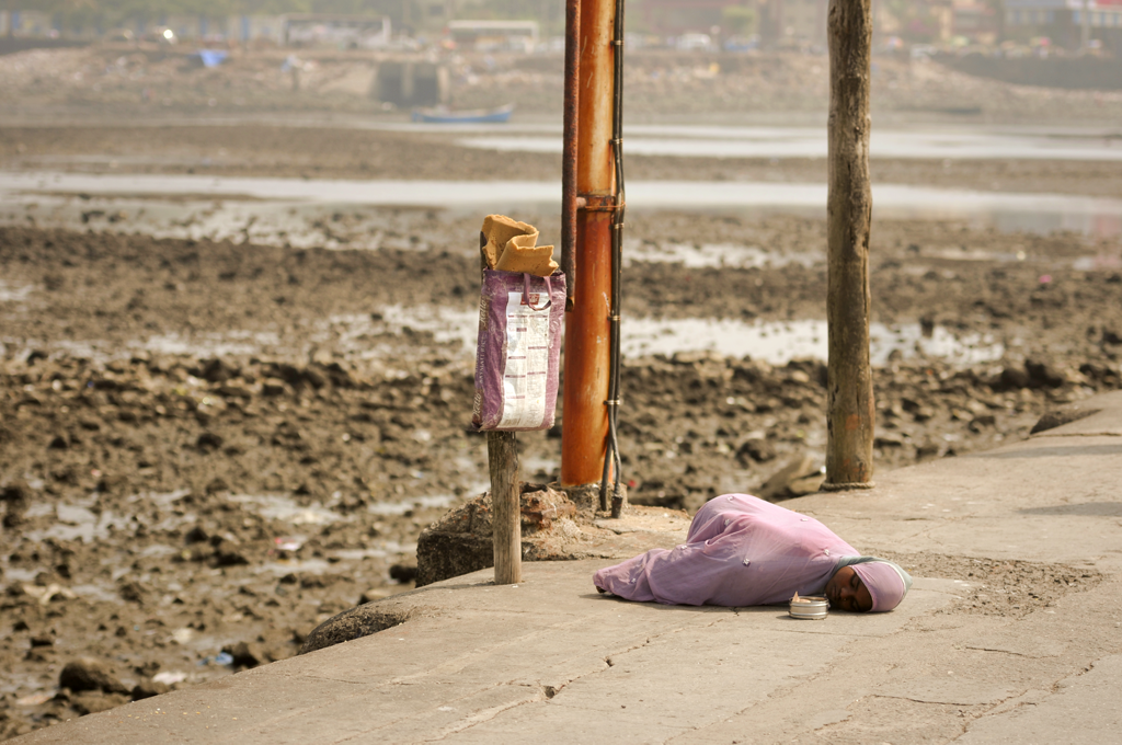 Photo of an Indian girl laying down on the pavement in Mumbai, India.