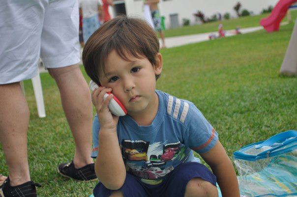 Beautiful brown eyed boy 2 years age holding phone loking bored and cute