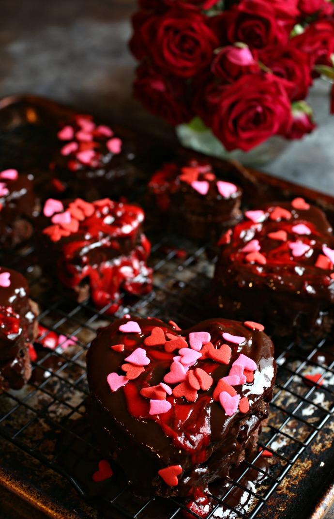 Recipe for heart shapes cut out of a chocolate sheet cake and topped with ganache and sprinkles.
