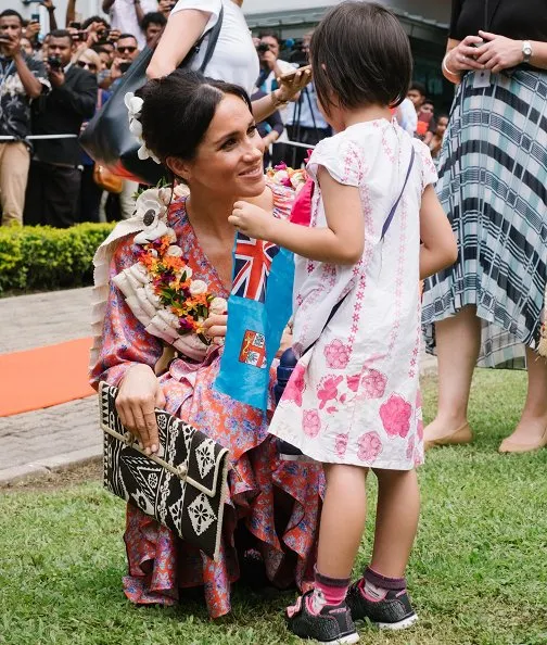 Meghan Markle wore Figue Frederica printed ruffle dress and Castañer Carina Black canvas wedge, and she wore Karen Walker gold stud earrings