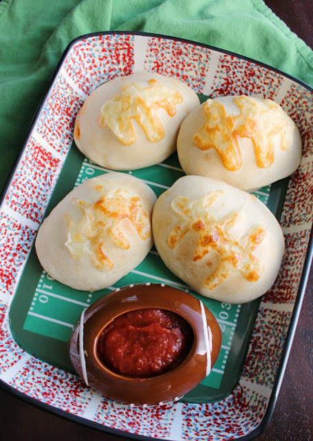 Make stuffed pizza footballs for your big game party! They are cute and easy. They could also be made into a super fun dinner. Platter of football stuffed pizzas with small football dish of pizza sauce for dipping