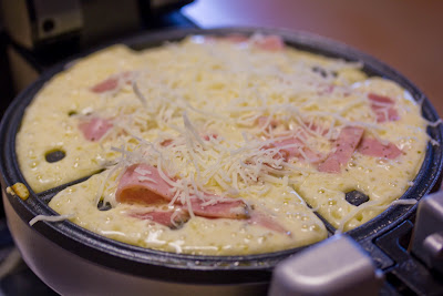 waffle batter, ham and cheese cooking in a waffle maker