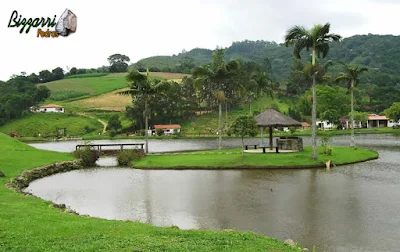 Construção do lago em sítio em Nazaré Paulista-SP com os muros de pedra rústica com a ponte de pedra e o quiosque de piaçava.