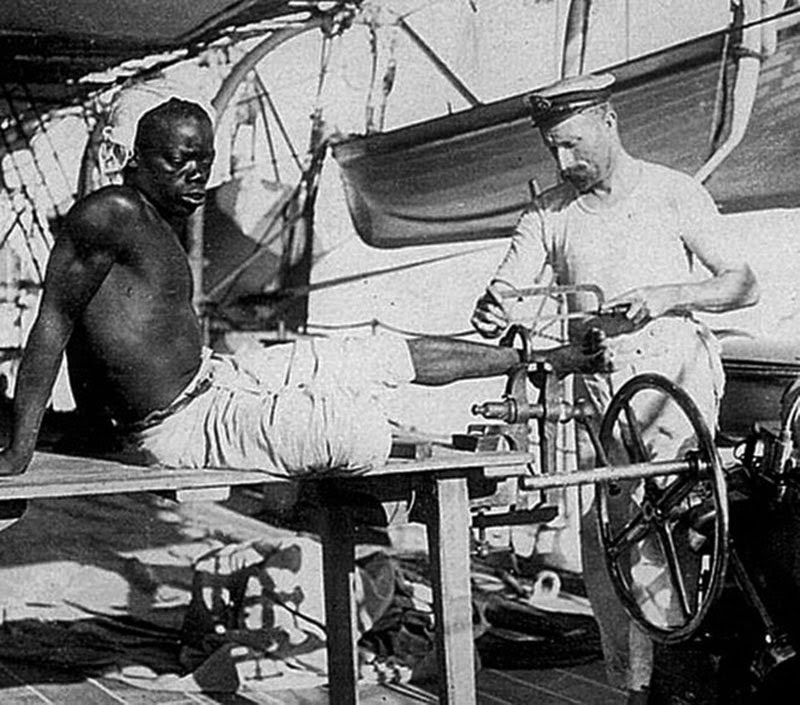 A British blacksmith removing the leg irons off a slave, 1907