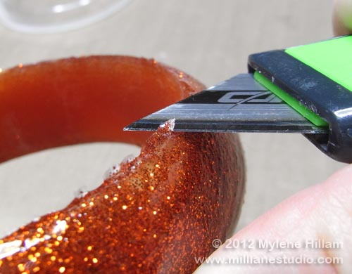 Using a utility knife to trim away the uneven edges of the resin