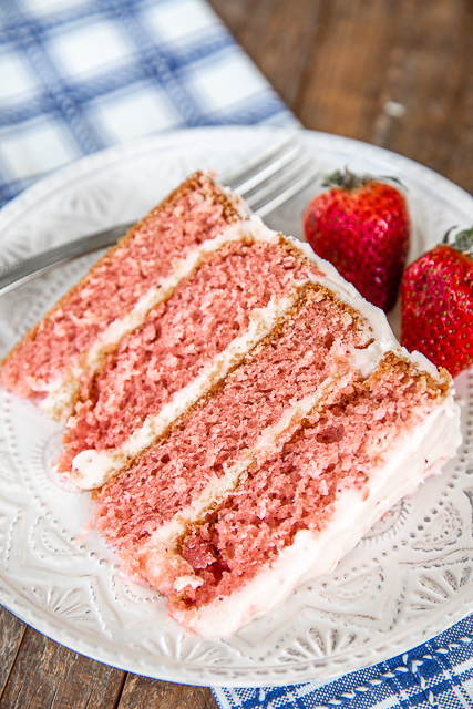 Homemade Strawberry Layer Cake with Strawberry Cream Cheese Frosting Recipe - hands down the best strawberry cake EVER! Better than any bakery! SO easy to make and tastes amazing. Sugar, self-rising flour, strawberry jello, frozen sliced strawberries, vegetable oil, ricotta cheese, cream cheese, butter, powdered sugar, and strawberry extract. SO moist and packed full of strawberry flavor. Perfect for parties, holidays, and birthdays! #cake #strawberrycake slice of strawberry layer cake on a plate