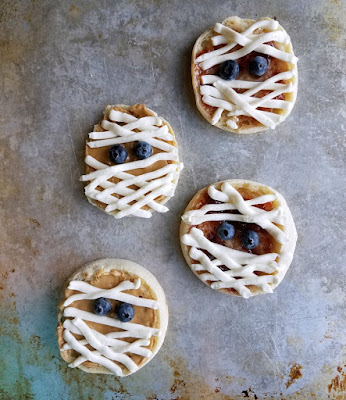 These super simple English muffin mummies are a perfect way to start Halloween. Just a couple of minutes and a few ingredients is all it takes to get the day off on an undead foot! mummies made and ready to eat