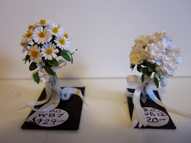 Two miniature posies of flowers: on the left is a bunch of daisies with a price sticker saying $29. On the right, a bunch of hydrangeas with a price sticker saying $20.