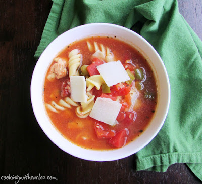 This flavorful chicken and vegetable soup is easy, delicious and healthy. Plus it's all made in a slow cooker while you do something else. Top with cheese for a perfect dinner on a cold night. bow of tomato and pepper chicken and noodle soup with cheese on top