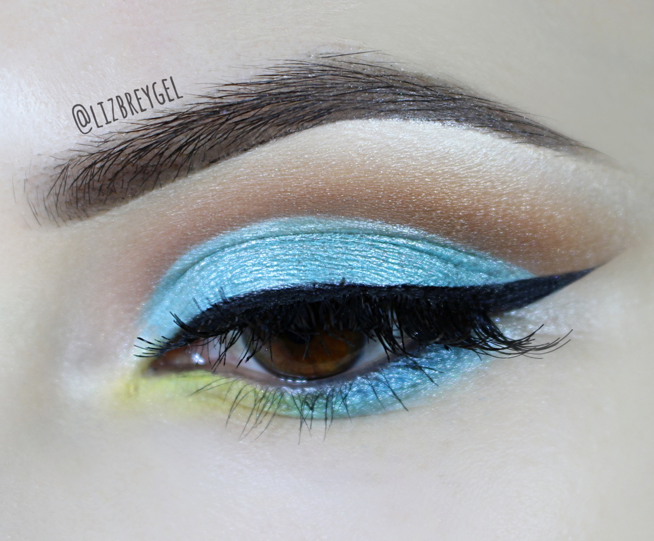 a close-up of a brown eye with a beautiful turquise-blue makeup look for summer