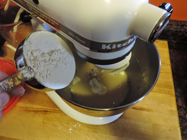 All purpose flour being added to the yeast, salt, sugar, and shortening mixture.