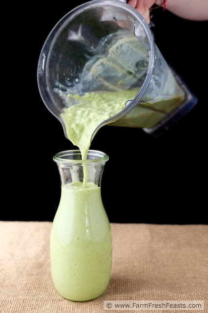 Image of a blender of peanut butter spinach and banana smoothie being poured into a glass