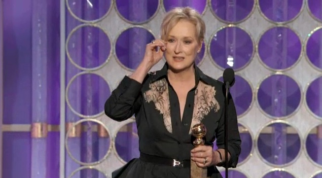 Meryl Streep at podium holding award, looking befuddled
