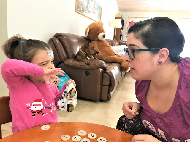 Mother and daughter sit at a small table playing an animal print matching game.