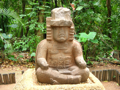 An Olmec stone statue depicting a man seated in a yogic posture called Sukhasana with his fingers in the Gyana Mudra position