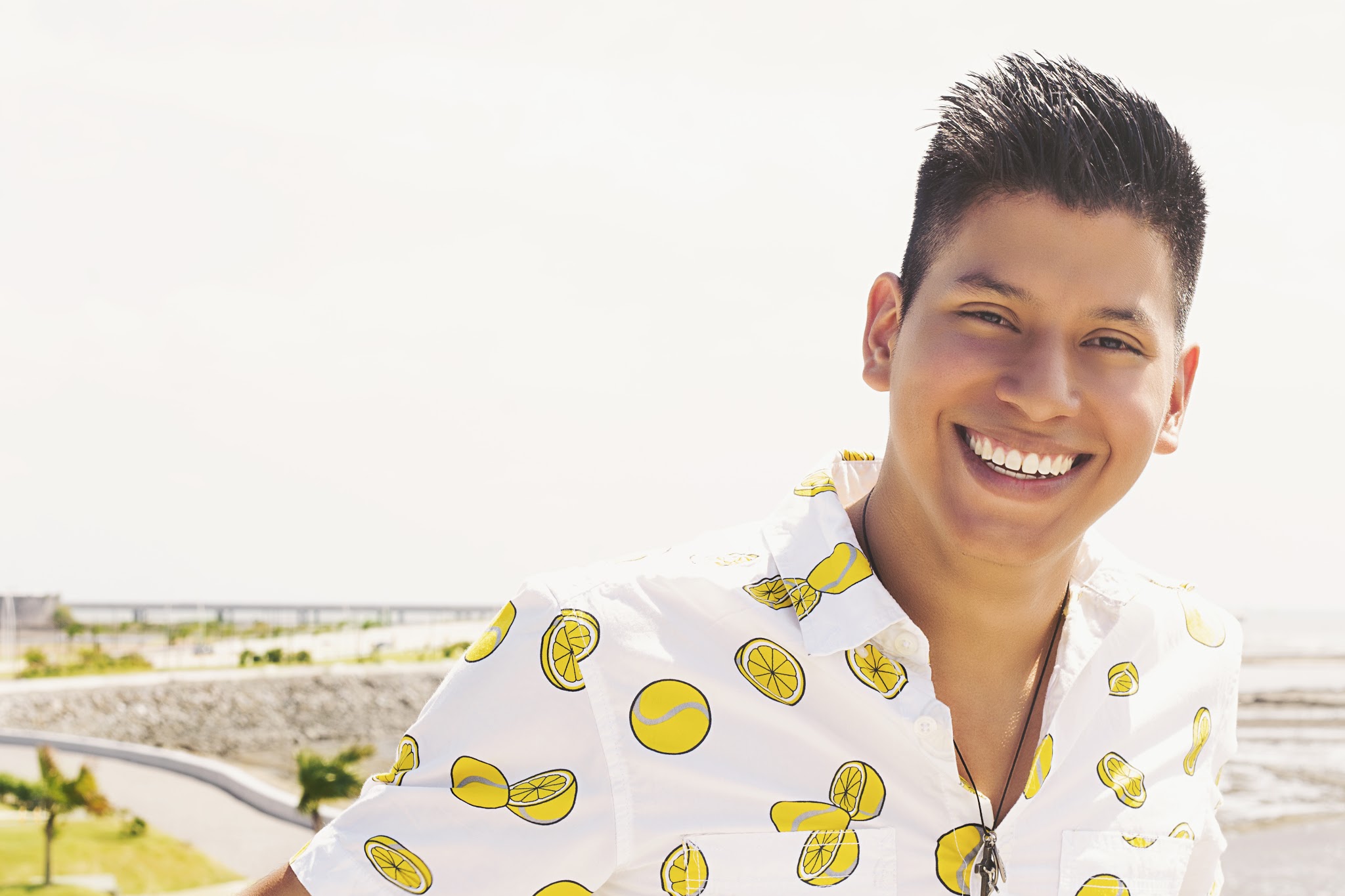 A man smiling big in a lemon shirt