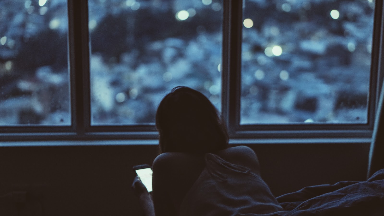 夜の暗い部屋でスマホを使っている少女