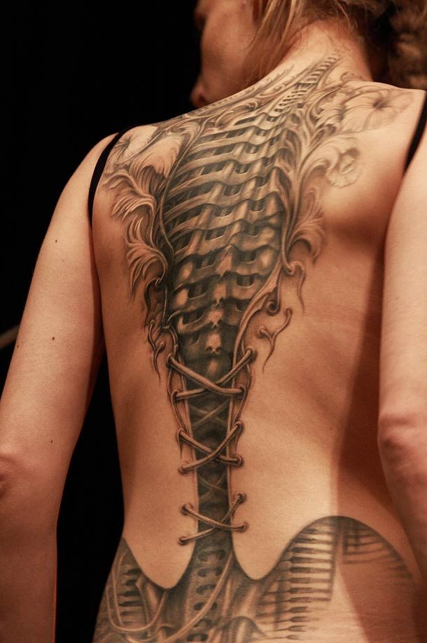 tatuaje realista en la espalda de una chica que parece sin piel que se ven las costillas de acero