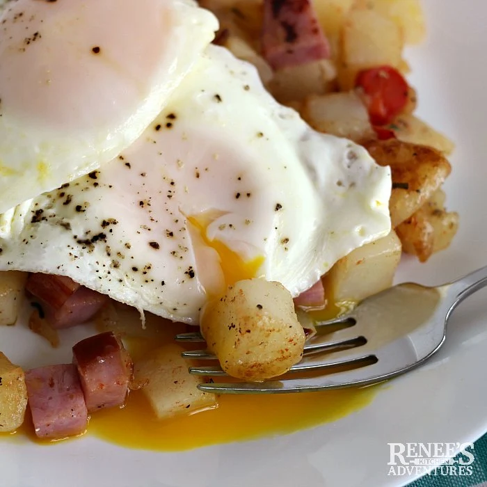 Ham Hash by Renee's Kitchen Adventures topped with an egg with the yolk running onto a fork and a piece of potato