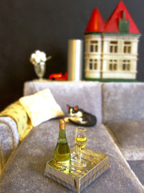 Miniature scene with grey velvet modern miniature chaise sofa, sleeping cat, champagne and miniature dolls house