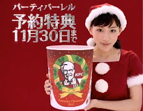 A young Japanese woman in a Santa-style outfit holding a bucket of Kentucky Fried Chicken. There is a red background with white Japanese lettering.