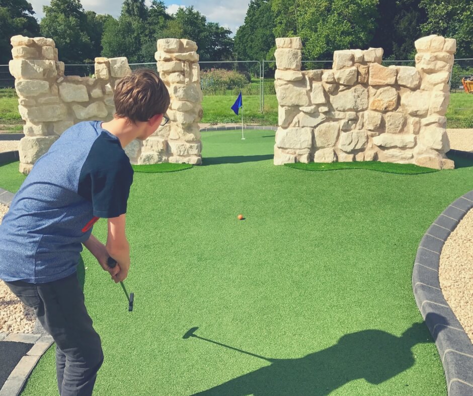 Teen attempts to hit golf ball between two walls, getting hole in one.