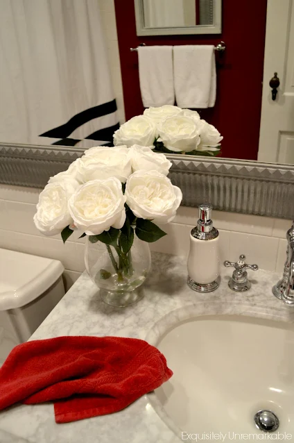 White flowers in a vase on a marble bathroom vanity