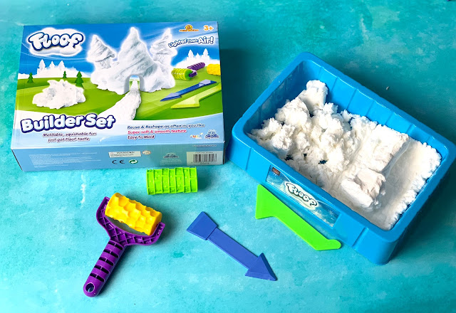 A Floof Builder set box next to a play tray with white Floof and and some tools