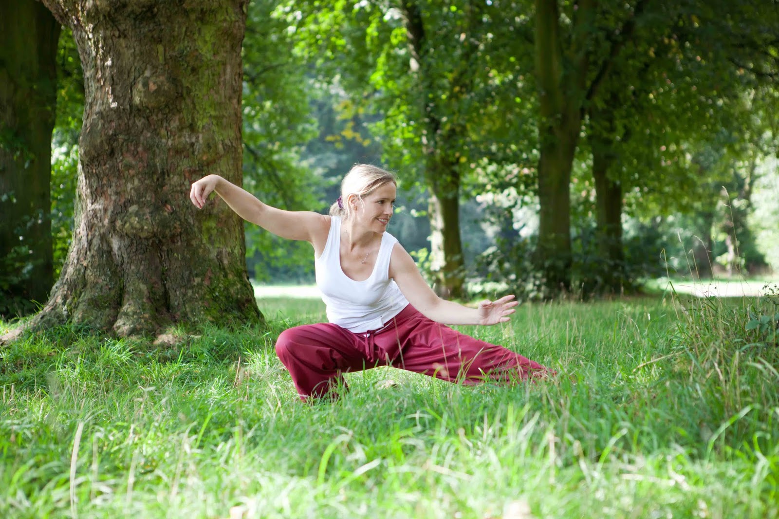 Sunzi und Taoismus Frau in roter Hose und weißem Shirt beim Tai Chi im Park