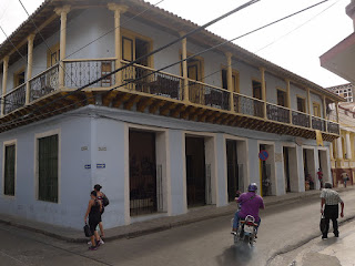 Santiago de Cuba, Calle Heredia, Casa de Estudiante und Casa de Trova. Santiago de Cuba, Calle Heredia, Casa de Estudiante und Casa de Trova. Hellblaues Haus mit riesigen offenen Fenstern zur Strape und umlaufendem Balkon im ersten Stock.