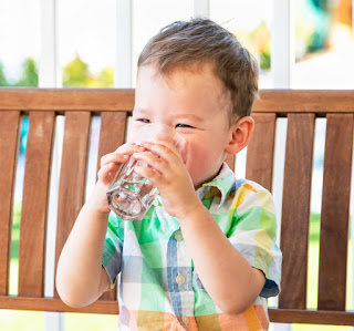 Kleinkind Junge trinkt Wasser aus einem Glas 