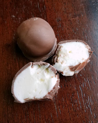 Bites of creamy orange cheesecake goodness are dipped in chocolate to make this one of a kind no bake treat! a whole truffle next to one cracked open to show the center