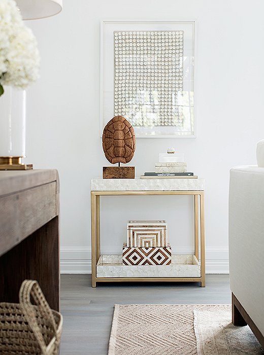 Inspiring interior design in a modern living room. The bar cart is covered in capiz—part of the mission to add rich texture everywhere. “There’s no real color here,” Alex says, “but the capiz makes the whole spot dynamic.” And by tucking the shell and books below, Erin and Gabe can easily turn the spot into a setup for drinks when they entertain.