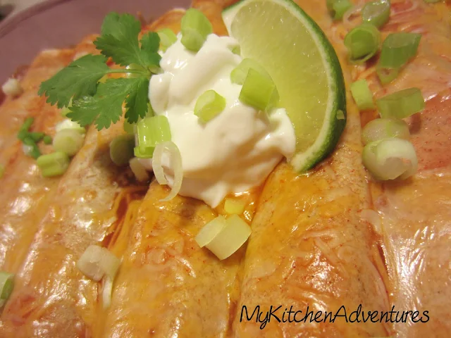 Chicken and Zucchini Enchiladas with sour cream, lime wedge and cilantro garnish