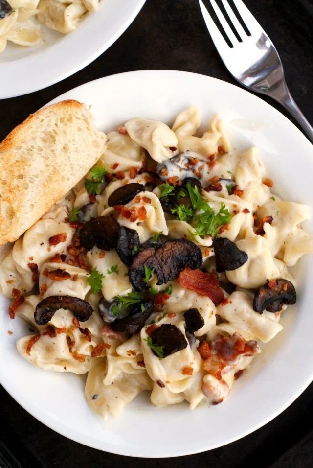 Parmesan Tortellini with Mushrooms and Bacon is a creamy and cheesy pasta dish featuring cheese tortellini swimming in a rich parmesan sauce tossed with caramelized mushrooms and smoky bacon.