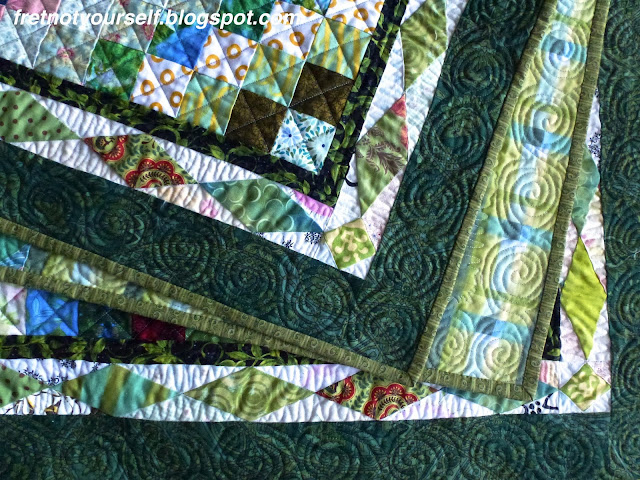 Detail of Scrappy Trip baby quilt with Diamond border Detail showing green diamond border and free-motion quilting.