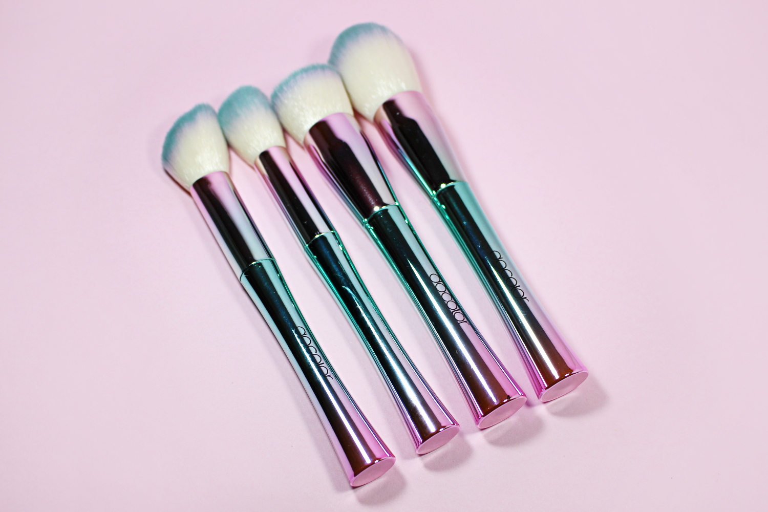 close-up of bright, iridescent makeup brushes on an eastehtic pink background
