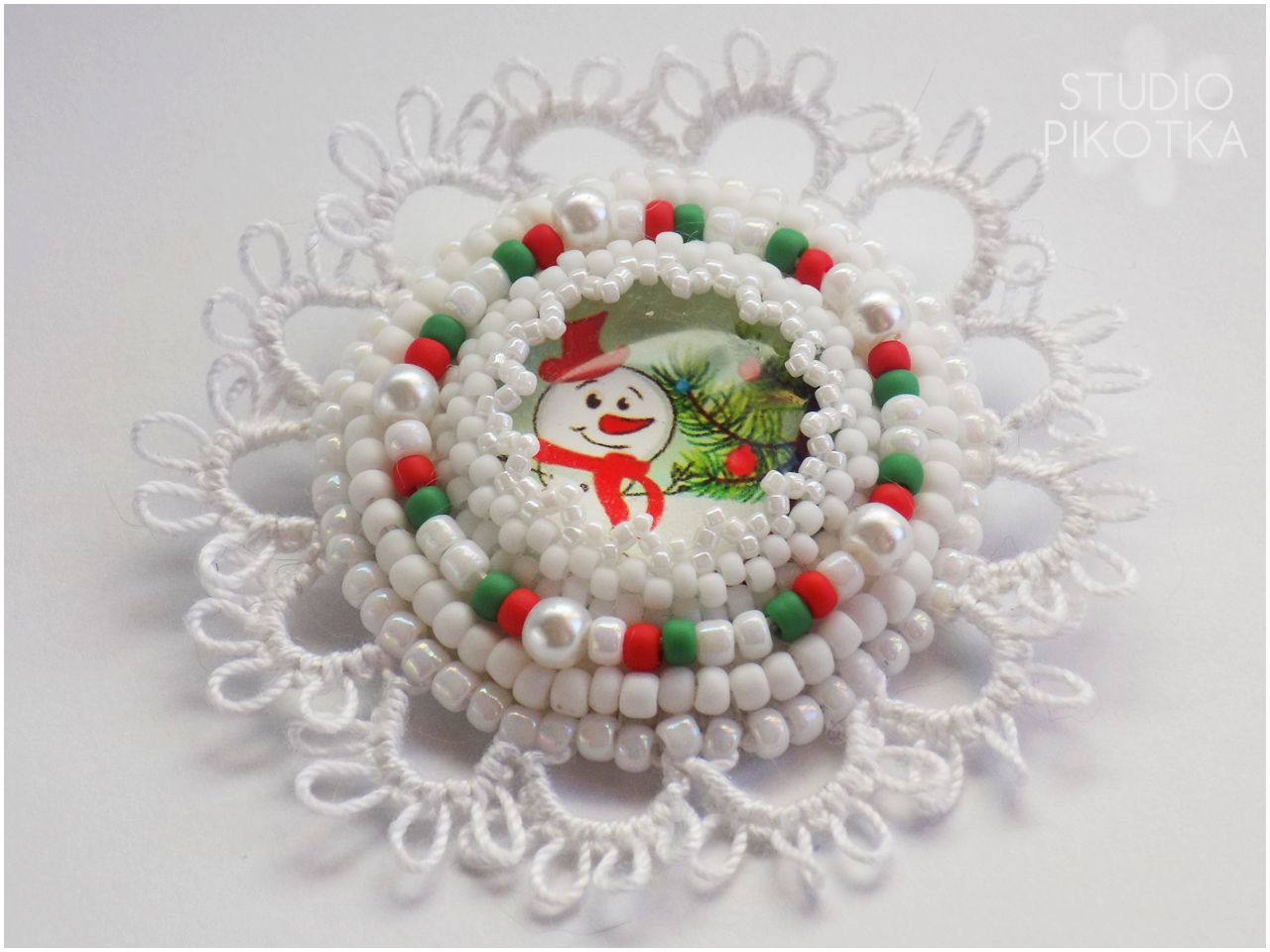 Broszka z bałwankiem będąca połączeniem haftu koralikowego i frywolitki. frywolitka, haft koralikowy, tatting, biżuteria, handmade, rękodzieło, broszka