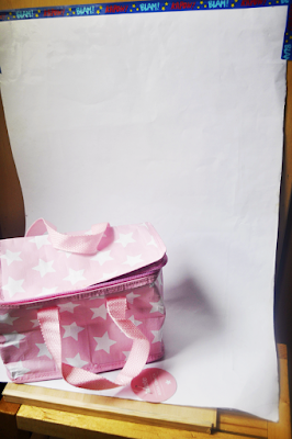 fondo infinito con Bolsa Térmica Tutete Rosa la bolsa sobre una cartulina blanca pegada con celo a una pared y a una silla