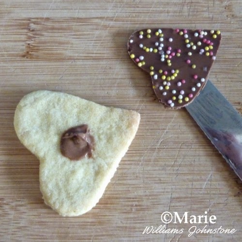 Adding chocolate heart with sprinkle decoration on to cookie base